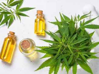 Cannabis oil in glass bottles and cannabis leaves at white table