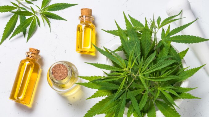 Cannabis oil in glass bottles and cannabis leaves at white table Cannabis oil in glass bottles and cannabis leaves at white table