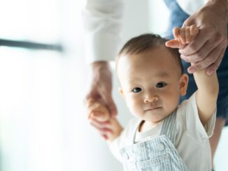 toddler baby learning to walk and having support by family together, little child with father