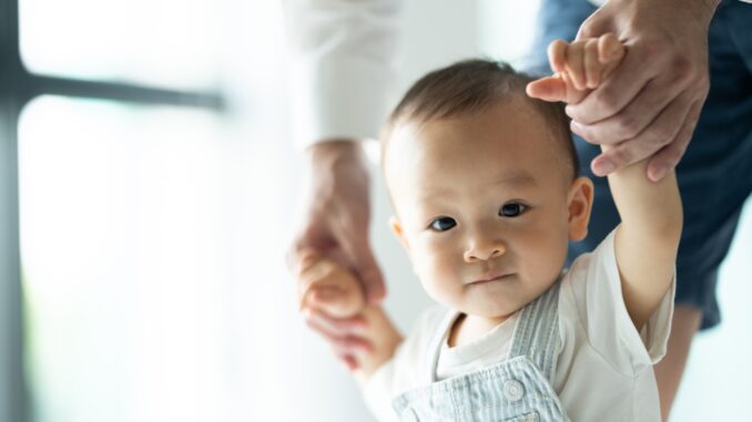 toddler baby learning to walk and having support by family together, little child with father toddler baby learning to walk and having support by family together, little child with father